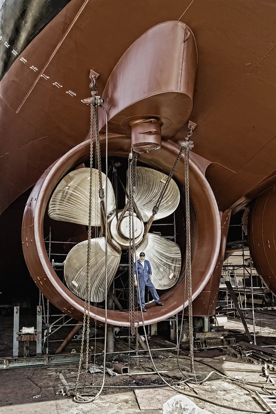 Großer Schiffspropeller in der Werft, Arbeiter steht davor