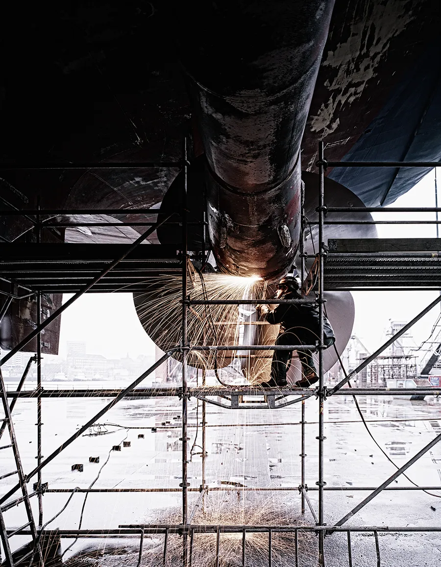 Schweißer arbeitet an der Propelleranlage eines Schiffs in der Werft